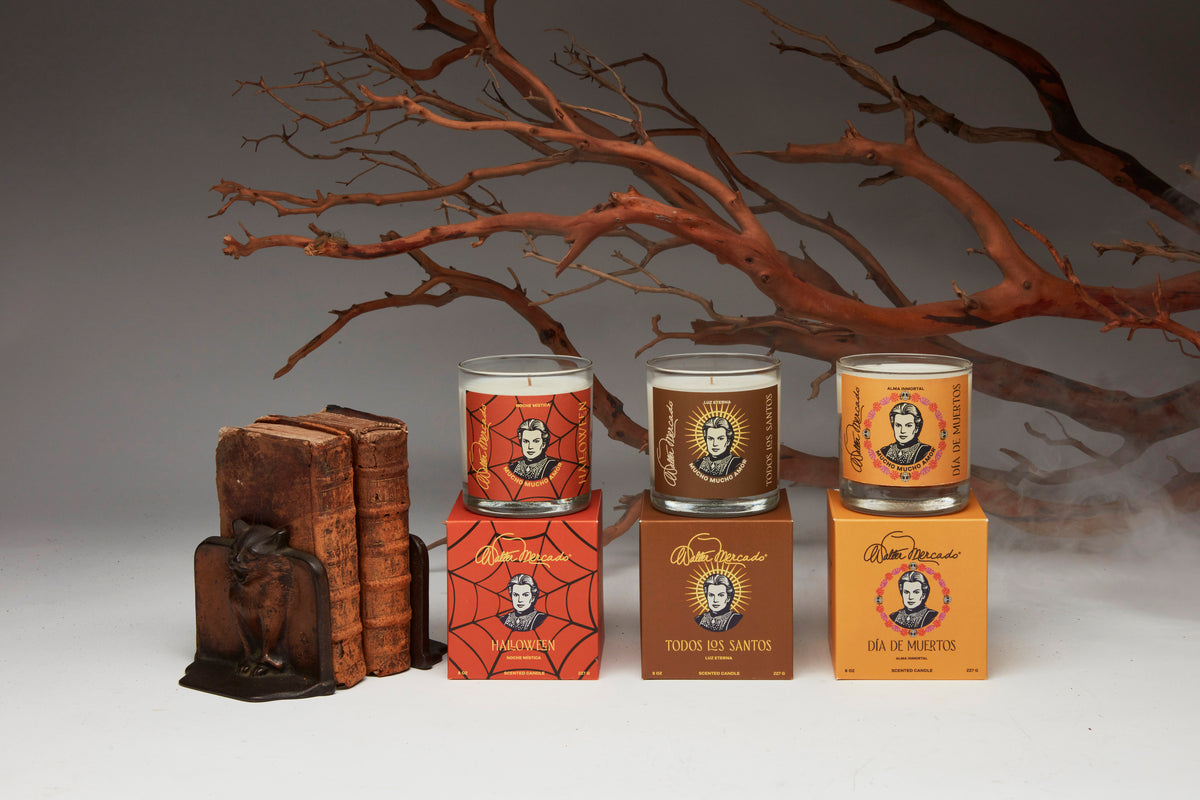 Walter Mercado Halloween, Todos los Santos, and Día de Muertos candles with their matching boxes, styled with branches and antique books.
